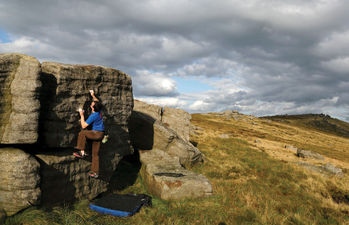 Bouldering in a beautiful moorland setting. Rick Legge pinches and crimps his way up Neckrest (V1) on The Settee Boulders. The Trig Point Boulders are in the far distance. Photo: © David Simmonite